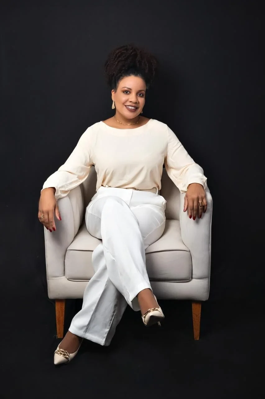 Luciana Santos em um retrato profissional, vestindo branco e sentada em uma poltrona.